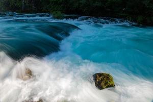 einzelner Stein im wilden Fluss foto