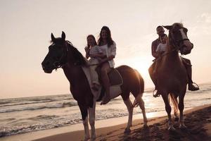 die familie verbringt zeit mit ihren kindern beim gemeinsamen reiten an einem wunderschönen sandstrand in sunet. foto