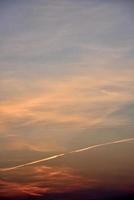 schönes Sonnenuntergangslicht und Wolken und eine Spur des Flugzeugs. Abendsonnenunterganglandschaft im Sommer. foto