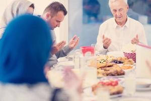 Moderne multiethnische muslimische Familie betet vor dem Iftar-Abendessen foto