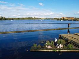 Kameraaufnahmen einer wunderschönen Luftdrohne von Willen Lake und Park, der sich in Milton Keynes, England, befindet. Die Menschen genießen an einem heißen sonnigen Sommertag am See foto