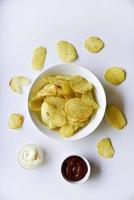 gewellte Kartoffelchips mit Pfeffer auf weißem Hintergrund. leckere Fast-Food-Chips. mit Soße. foto