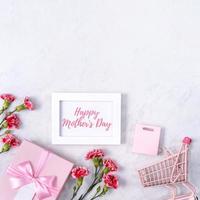 Happy Mother's Day Hintergrunddesignkonzept mit Grußworten, schöner rosafarbener, roter Nelkenblumenstrauß auf Marmortisch, Draufsicht, flache Lage, Kopierraum. foto
