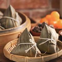 Reisknödel - chinesisches Zongzi-Essen in einem Dampfgarer auf Holztisch mit roter Ziegelwand, Fensterhintergrund zu Hause für Drachenboot-Festival-Konzept, Nahaufnahme. foto