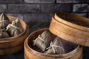 Reisknödel, Zongzi - chinesischer Reisknödel Zongzi auf schwarzem Backsteinhintergrund, Schiefertisch, Konzept des traditionellen Essens des Drachenbootfestivals, Nahaufnahme. foto