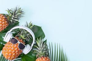 lustige ananas mit weißem kopfhörer, konzept des musikhörens, isoliert auf farbigem hintergrund mit tropischen palmblättern, draufsicht, flaches lagdesign. foto
