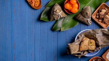 reisknödel, zongzi - traditionelles chinesisches essen auf blauem holzhintergrund des drachenbootfestivals, duanwu-festival, draufsicht, flaches lag-designkonzept. foto