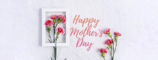 Happy Mother's Day Hintergrunddesignkonzept mit Grußworten, schöner rosafarbener, roter Nelkenblumenstrauß auf Marmortisch, Draufsicht, flache Lage, Kopierraum. foto