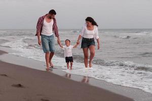 Die Familie genießt ihren Urlaub, während sie mit ihrem Sohn am Sandstrand spazieren geht. selektiver Fokus foto