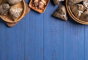 Konzept des Drachenbootfestivals - Reisknödel, Zongzi, traditionelles chinesisches Essen auf blauem Holzhintergrund für das Duanwu-Festival, Draufsicht, flaches Designkonzept. foto