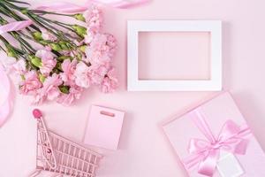 muttertag, valentinstag hintergrunddesignkonzept, schöner rosa nelkenblumenstrauß auf pastellrosa tisch, draufsicht, flache lage, kopierraum. foto