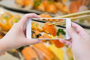 Fotografieren von Lachs-Sashimi in Essstäbchen foto