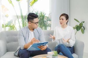 lächelnder junger asiatischer männlicher psychiater, der mit junger frau in seinem büro spricht. foto