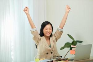 junge studentin gewinnerin feiern sieg triumph sitzen am heimschreibtisch foto