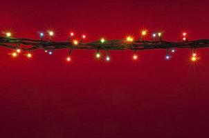 Weihnachtsbeleuchtung auf rotem Hintergrund. mehrfarbiges Licht. bunter heller hintergrund. foto
