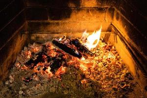 schwelendes Brennholz und heiße Asche im Kamin foto