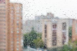 Regentropfen auf Fensterglas und verschwommenes Stadtbild foto