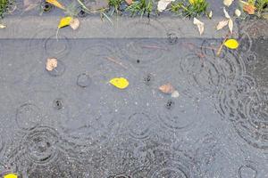 Pfütze auf asphaltiertem Fußweg im Herbstregen foto