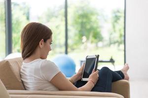 Frau sitzt auf Sofa mit Tablet-Computer foto