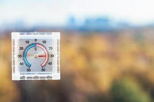 Thermometer am Fenster zu Hause und unscharfer Stadtpark foto