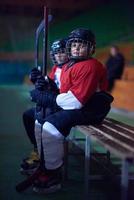 Kinder-Eishockeyspieler auf der Bank foto