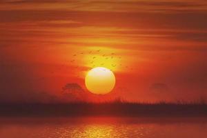 ruhiger Fluss und Wiesen bei Sonnenuntergang auf dem Land foto