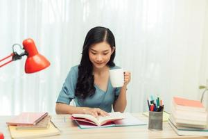 Freizeit. junge Frau mit Brille liest ein Buch, das zu Hause sitzt und Tee trinkt, foto