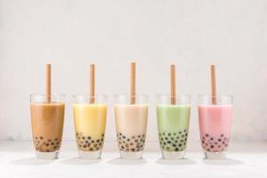 Reihe von frischen Boba Bubble Tea Gläsern mit Strohhalm auf weißem Hintergrund. foto