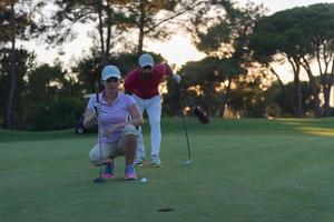 Paar auf dem Golfplatz bei Sonnenuntergang foto