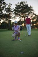 Paar auf dem Golfplatz bei Sonnenuntergang foto