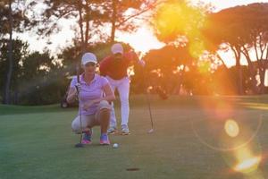 Paar auf dem Golfplatz bei Sonnenuntergang foto