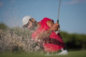 Golfspieler, der einen Sandbunkerschlag schlägt foto