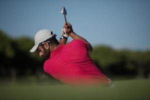 Golfspieler, der einen Sandbunkerschlag schlägt foto