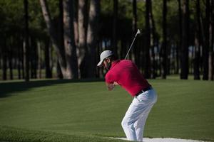 Golfspieler, der einen Sandbunkerschlag schlägt foto