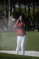 Golfspieler, der einen Sandbunkerschlag schlägt foto