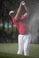Golfspieler, der einen Sandbunkerschlag schlägt foto
