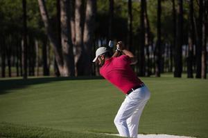 Golfspieler, der einen Sandbunkerschlag schlägt foto