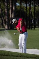 Golfspieler, der einen Sandbunkerschlag schlägt foto