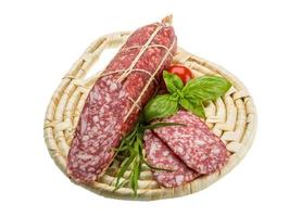 Salami auf Holzplatte und weißem Hintergrund foto