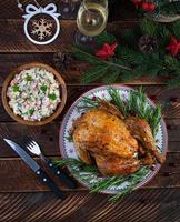 Gebackenes ganzes Huhn oder Truthahn zu Weihnachten. neujahrstisch mit dekoration, hausgemachtem gebratenem huhn, wein und salat. Ansicht von oben