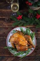 Gebackenes ganzes Huhn oder Truthahn zu Weihnachten. neujahrstisch mit dekoration, hausgemachtem gebratenem huhn, wein und salat. Ansicht von oben foto