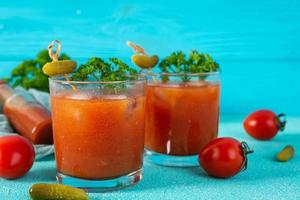 Alkoholcocktail Bloody Mary auf blauem Hintergrund. Klassischer Cocktail mit Tomatensaft und Wodka foto