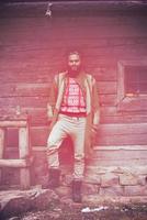 Porträt eines jungen Hipsters vor einem Holzhaus foto