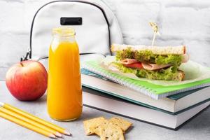 Snack für die Schule mit Sandwich, frischem Apfel und Orangensaft. bunte Schulsachen, foto