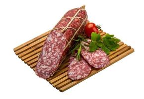 Salami auf Holzplatte und weißem Hintergrund foto