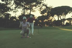 Paar auf dem Golfplatz bei Sonnenuntergang foto