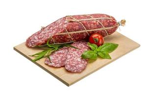 Salami auf Holzplatte und weißem Hintergrund foto