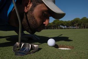Golfspieler bläst Ball ins Loch foto