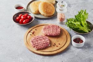 Rohe Kalbshackfleisch-Burger-Steakkoteletts auf Holzschneidebrett