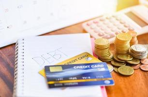 Taschenrechner und Münzstapel auf Notizbuchpapier mit Schuldenkreditkarte im Büro Finanzzählung - Schuldenmanagementkonzept foto